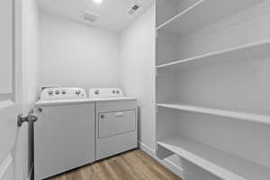 Clothes washing area featuring washing machine and clothes dryer, light wood-style floors, laundry area, and visible vents