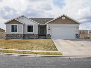 View of front of home featuring fence, a front yard, stone siding, and a garage