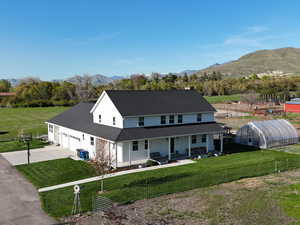 View of front facade featuring a greenhouse, a porch, asphalt driveway, a mountain view, and an outbuilding