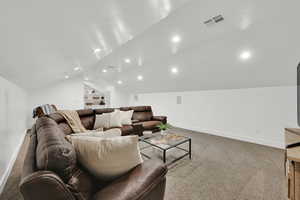 Carpeted home theater room with lofted ceiling, recessed lighting, and built in shelves