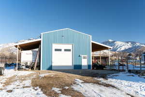 Snow covered structure featuring a mountain view, an outdoor structure, and fence