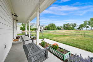 Covered porch with a mountain view and a yard