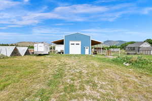 View of yard with a detached garage, a mountain view, an outdoor structure, and an outbuilding