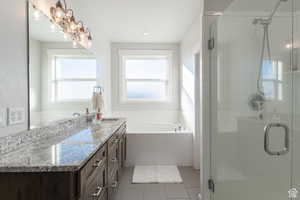 Full bathroom featuring a stall shower, tile patterned flooring, vanity, and a garden tub