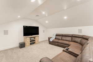 Media room featuring light colored carpet, visible vents, baseboards, and vaulted ceiling