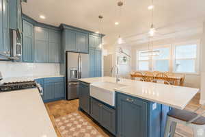 Kitchen with a kitchen bar, decorative light fixtures, stainless steel appliances, backsplash, and a sink