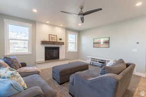 Living room featuring a large fireplace, baseboards, ceiling fan, wood finished floors, and recessed lighting