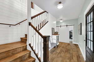 Entryway featuring a barn door, wood-type flooring, stairs, and wood walls