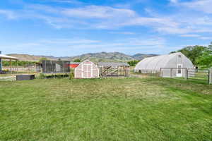 View of yard featuring a mountain view, a shed, an exterior structure, and a trampoline