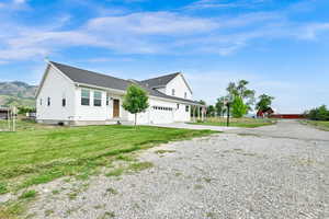 View of home's exterior featuring gravel driveway, a garage, a lawn, a shingled roof, and a mountain view