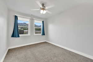Carpeted spare room featuring baseboards and a ceiling fan