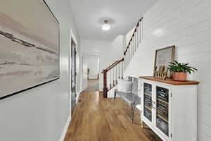 Foyer featuring stairway, wood finished floors, a dry bar, and wood walls