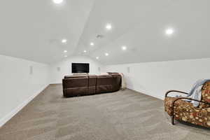 Carpeted home theater with lofted ceiling and recessed lighting