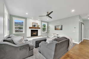 Living room featuring ceiling fan, light wood-type flooring, recessed lighting, and a fireplace
