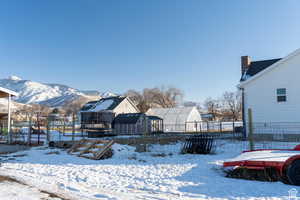 Yard covered in snow featuring fence, a storage unit, an outdoor structure, and a residential view