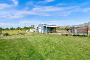 View of yard featuring a trampoline, an outdoor structure, a pole building, and a mountain view