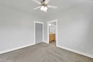 Carpeted spare room with a ceiling fan and baseboards