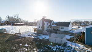 Snow covered rear of property featuring a storage unit, an outbuilding, an exterior structure, and fence