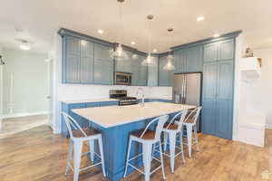 Kitchen featuring light countertops, a breakfast bar, appliances with stainless steel finishes, and tasteful backsplash