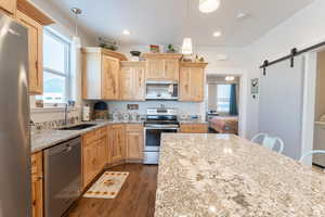 Kitchen with light brown cabinets, a sink, stainless steel appliances, and a barn door