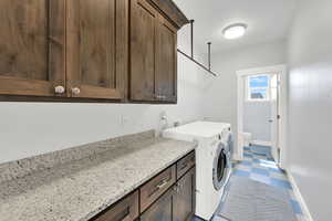 Laundry area featuring washing machine and clothes dryer, cabinet space, and tile patterned floors