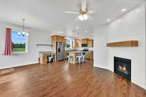 Living area with dark wood finished floors, recessed lighting, a ceiling fan, a large fireplace, and a chandelier