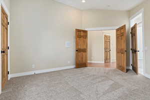 Unfurnished bedroom with baseboards, a towering ceiling, recessed lighting, and light colored carpet