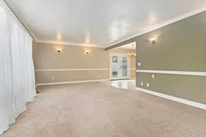 Unfurnished room featuring french doors, an inviting chandelier, ornamental molding, baseboards, and light carpet