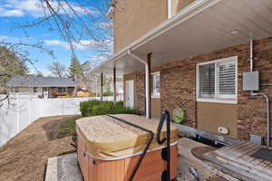 View of patio with fence and a hot tub