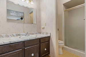 Bathroom with wallpapered walls, vanity, toilet, and a stall shower