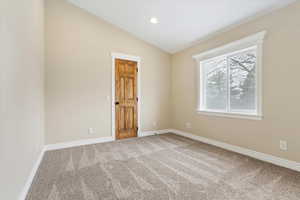 Carpeted empty room featuring baseboards, lofted ceiling, and recessed lighting