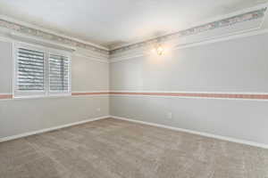 Carpeted empty room with baseboards and crown molding