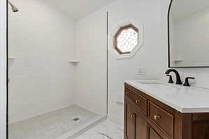 Full bathroom with marble finish floor, a stall shower, and vanity