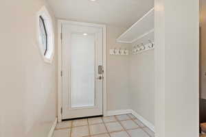 Doorway featuring light tile patterned floors and baseboards
