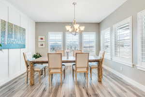 Dining room featuring baseboards, an inviting chandelier, and light wood-type flooring