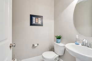 Half bathroom with baseboards, a sink, and toilet