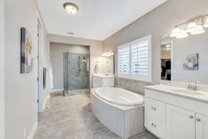 Full bath featuring a stall shower, a sink, two vanities, a spacious closet, and a bath