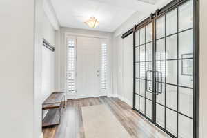 Entrance foyer featuring baseboards, a barn door, wood finished floors, and a healthy amount of sunlight
