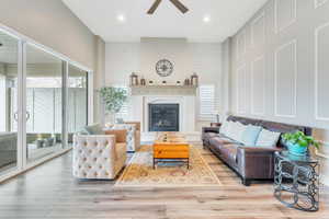 Living area featuring light wood-style flooring, recessed lighting, a glass covered fireplace, and ceiling fan
