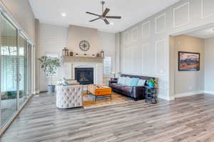 Living room featuring a glass covered fireplace, baseboards, light wood-style floors, ceiling fan, and recessed lighting