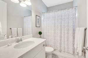 Full bathroom with toilet, vanity, and shower / bath combo