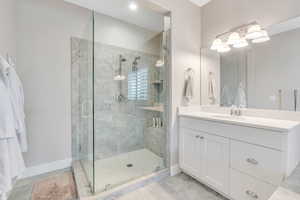 Bathroom with a stall shower, baseboards, tile patterned flooring, and vanity