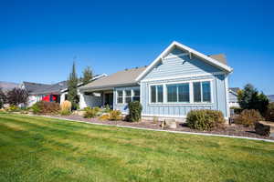 View of front facade with a front lawn and board and batten siding
