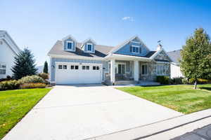 View of front of house with a garage, concrete driveway, a porch, and a front yard