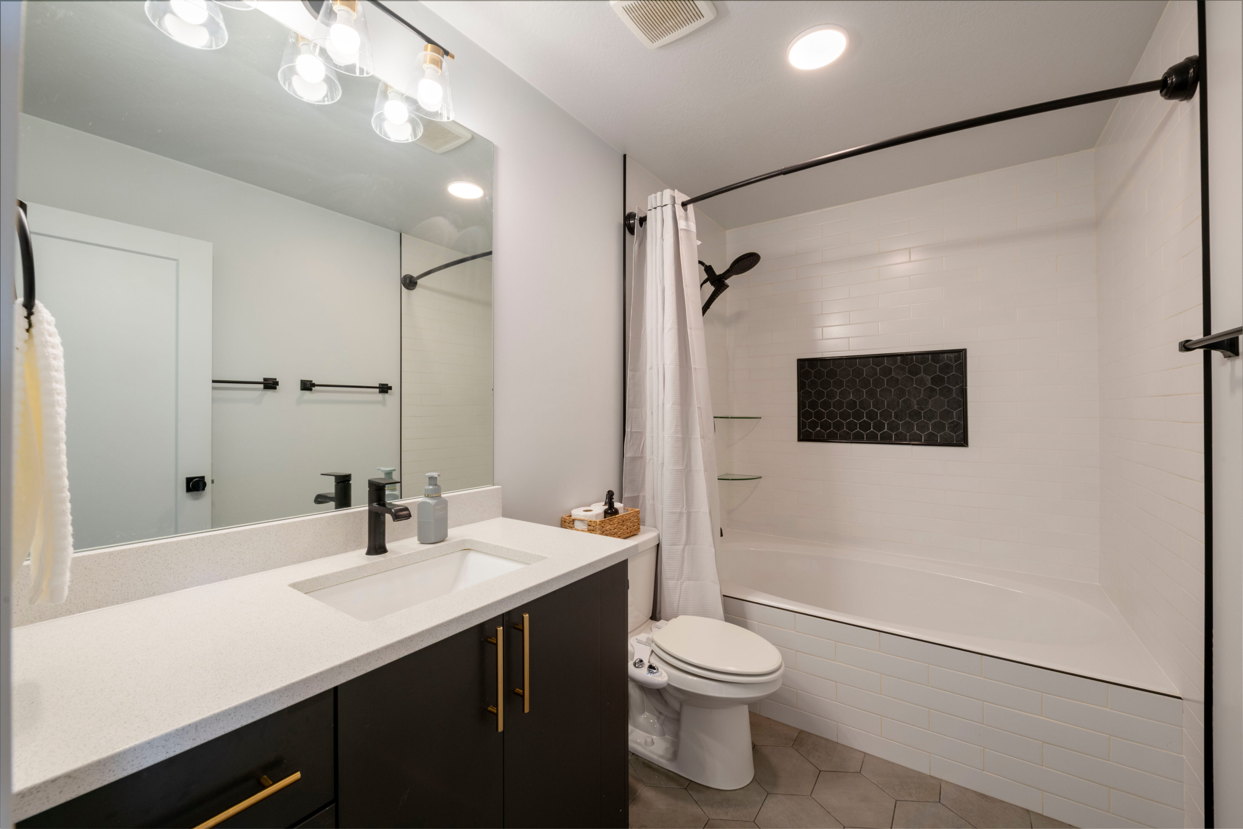 Bathroom featuring toilet, tiled shower / bath combo, vanity, tile patterned flooring, and visible vents