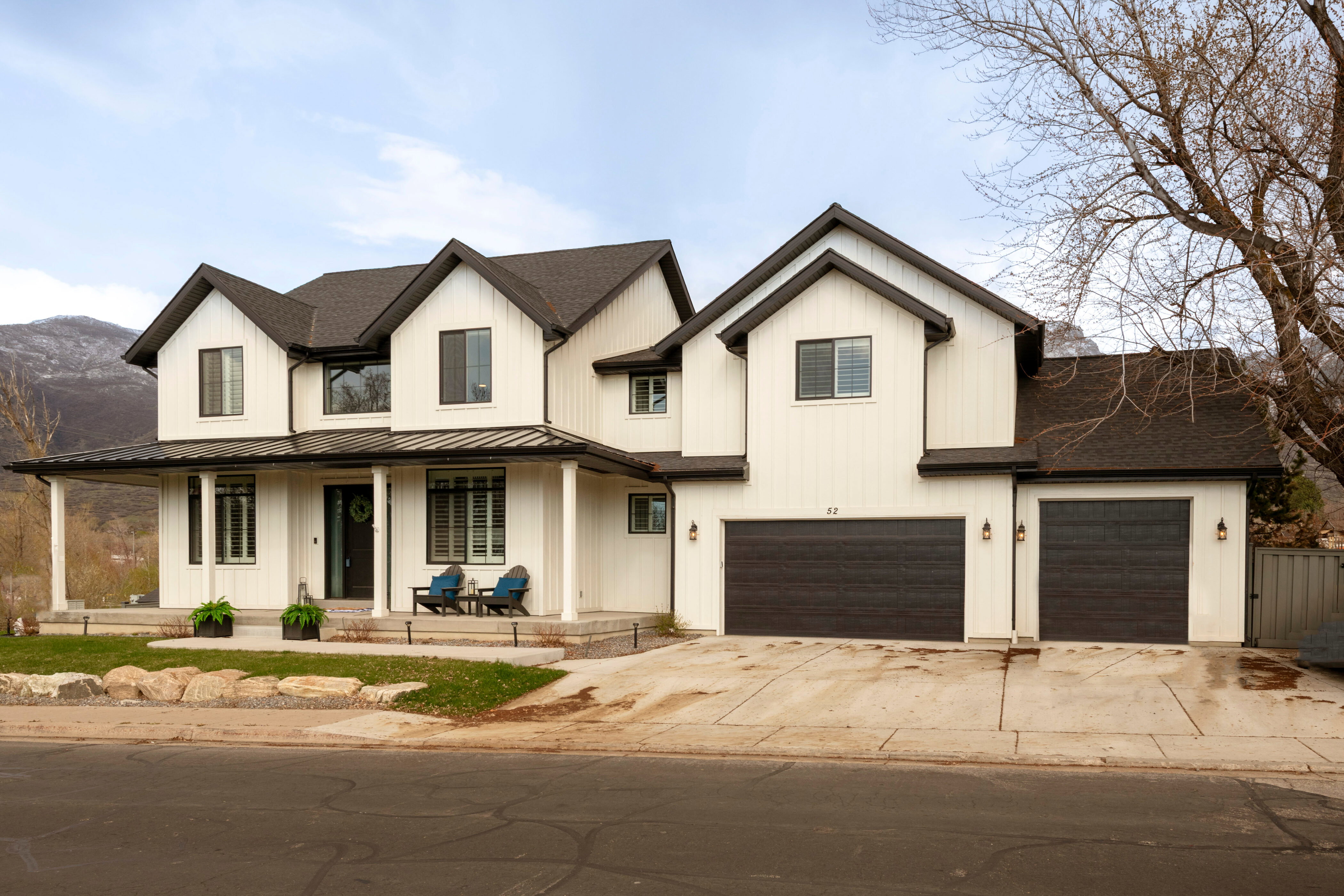 Modern inspired farmhouse with concrete driveway, a standing seam roof, board and batten siding, covered porch, and a garage