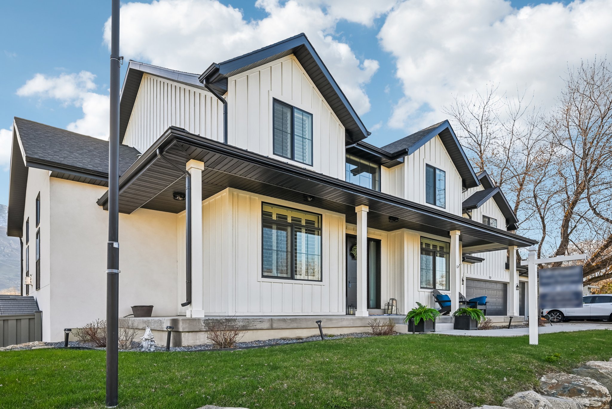View of front of house with board and batten siding, a front lawn, a garage, and a porch