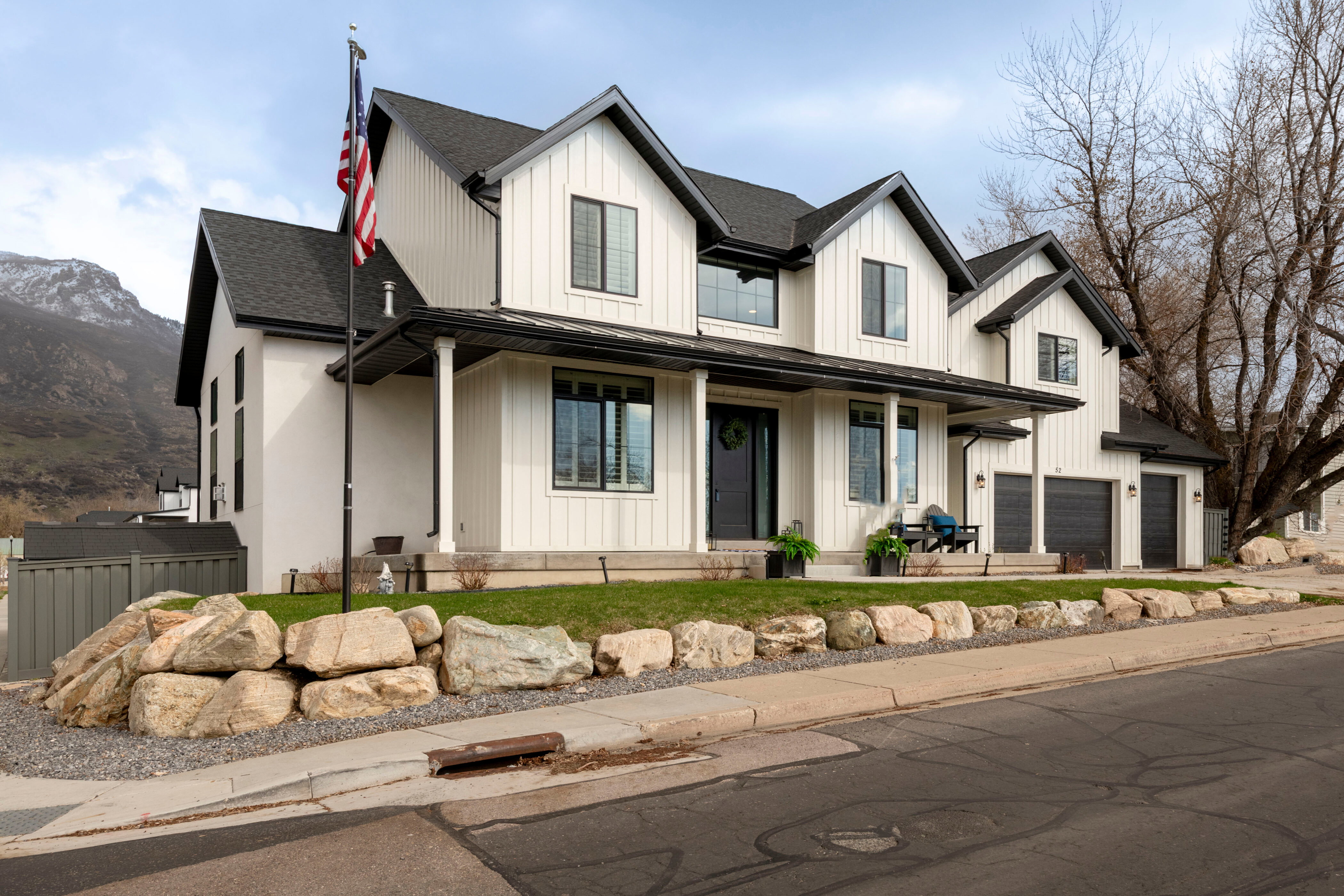 Modern farmhouse style home with board and batten siding, a porch, a garage, and fence