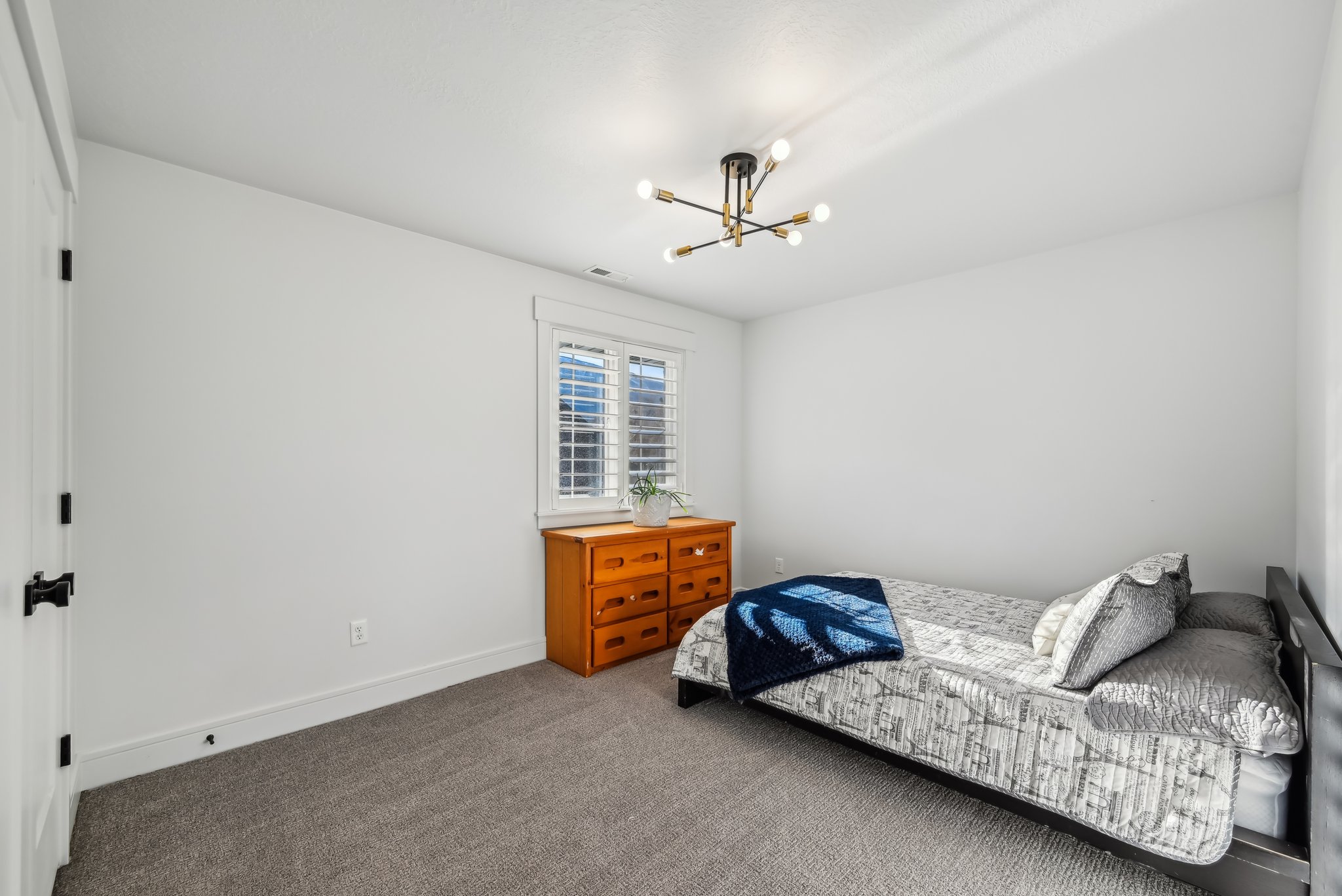 Carpeted bedroom with visible vents, baseboards, and a notable chandelier
