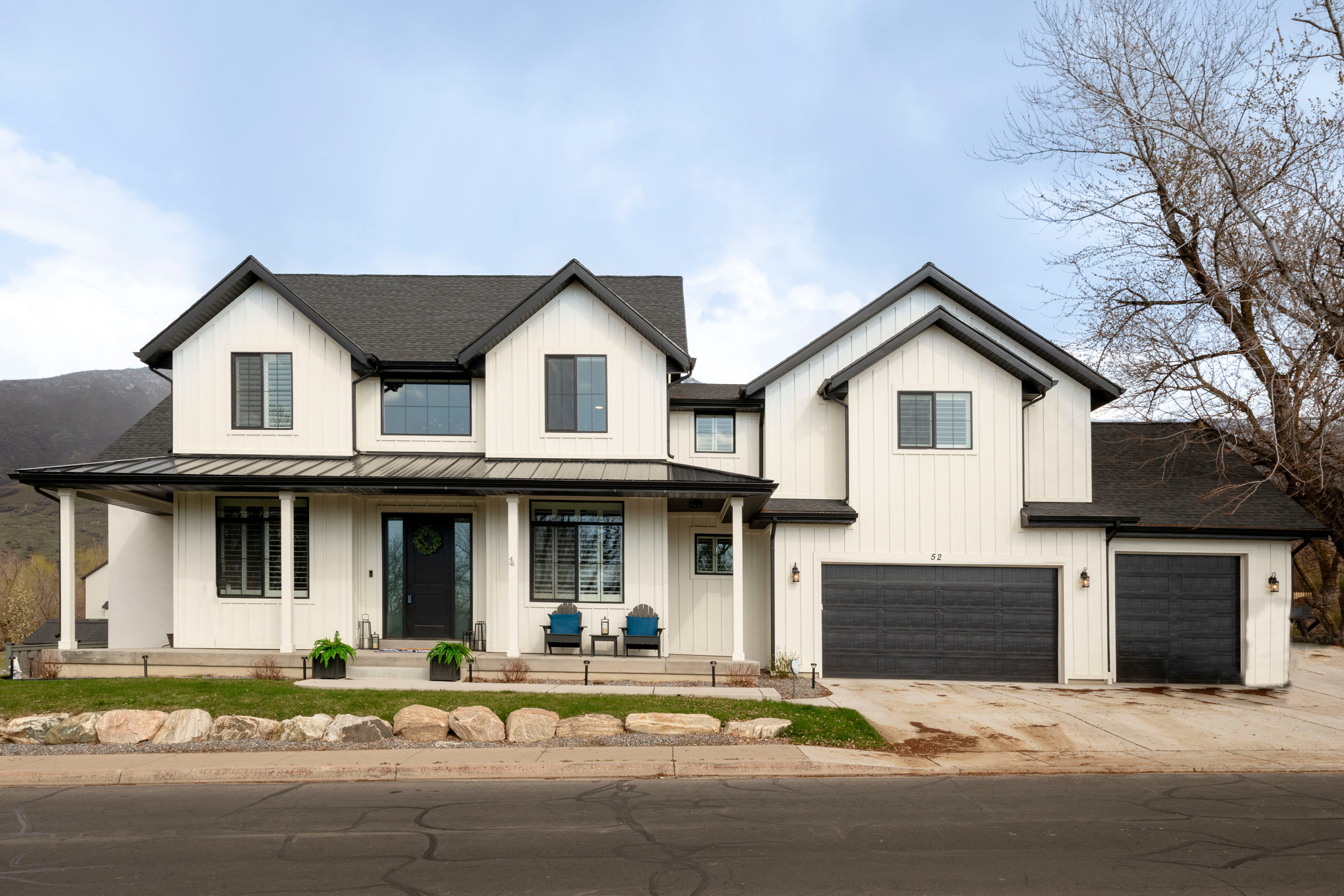 Modern farmhouse featuring covered porch, a standing seam roof, concrete driveway, an attached garage, and a shingled roof